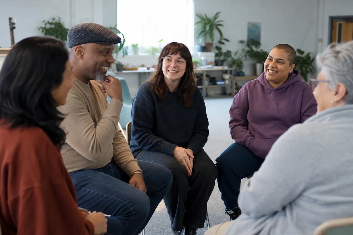 People sharing warm conversation in a welcoming autism community meeting space